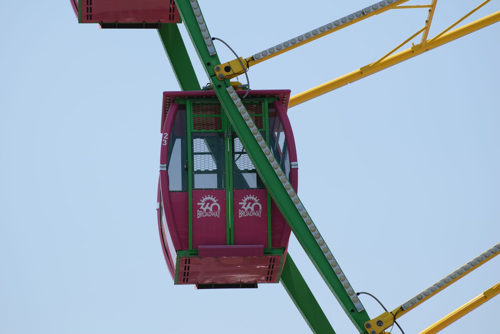 A red Ferris wheel gondola framed by green and yellow spokes, photographed by Mike Loerop
