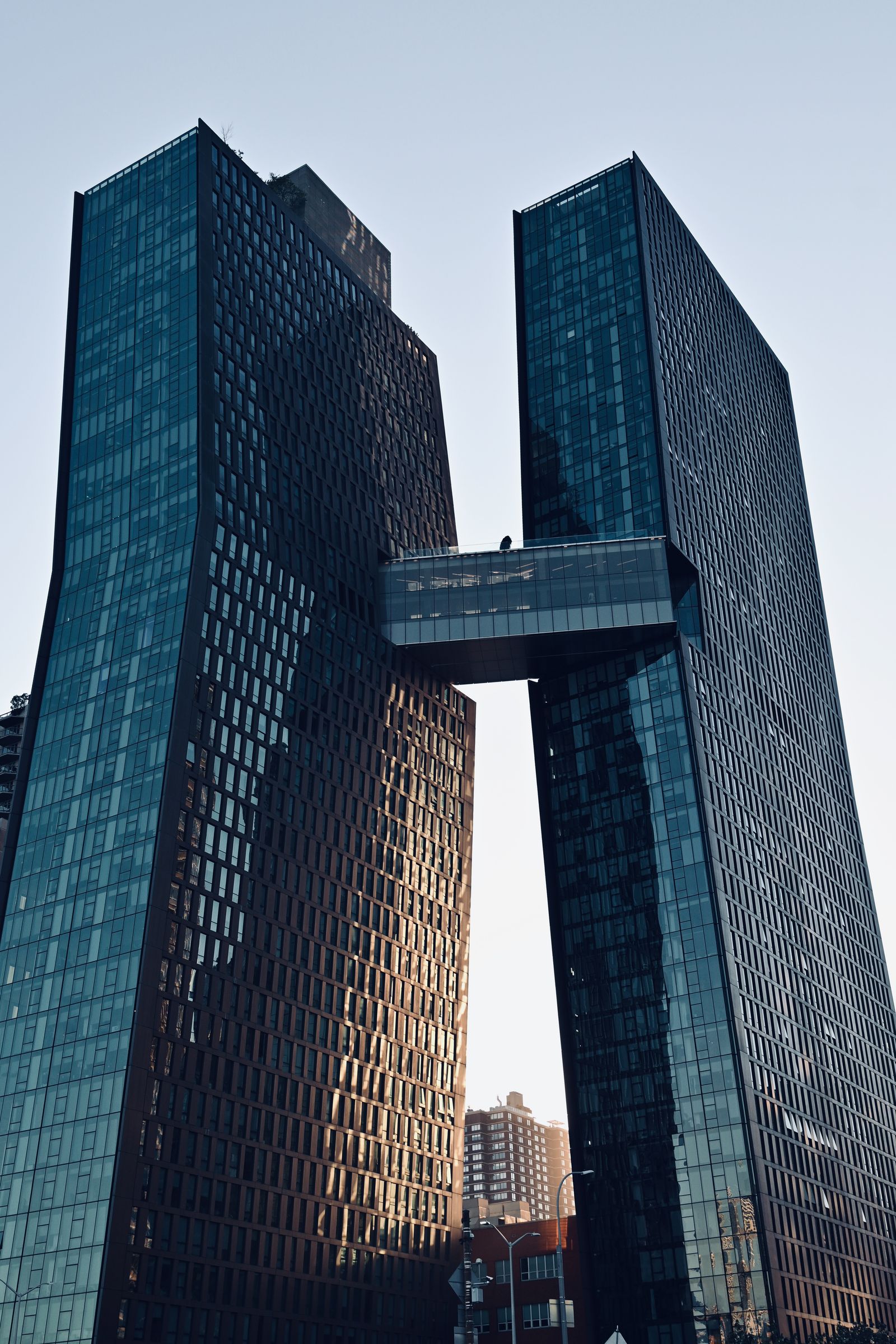 Two glass towers joined by a skybridge, photographed from below by Mike Loerop