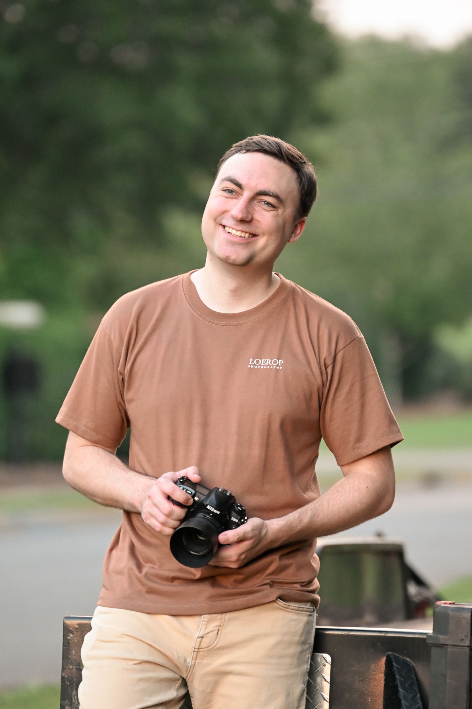 Mike Loerop smiling with his Nikon camera on a summer evening