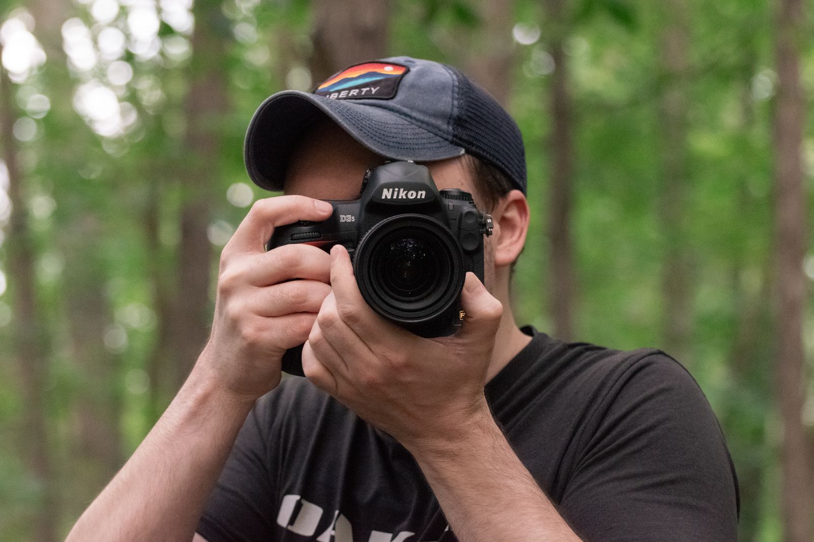 Mike Loerop raising his Nikon camera to photograph in the woods