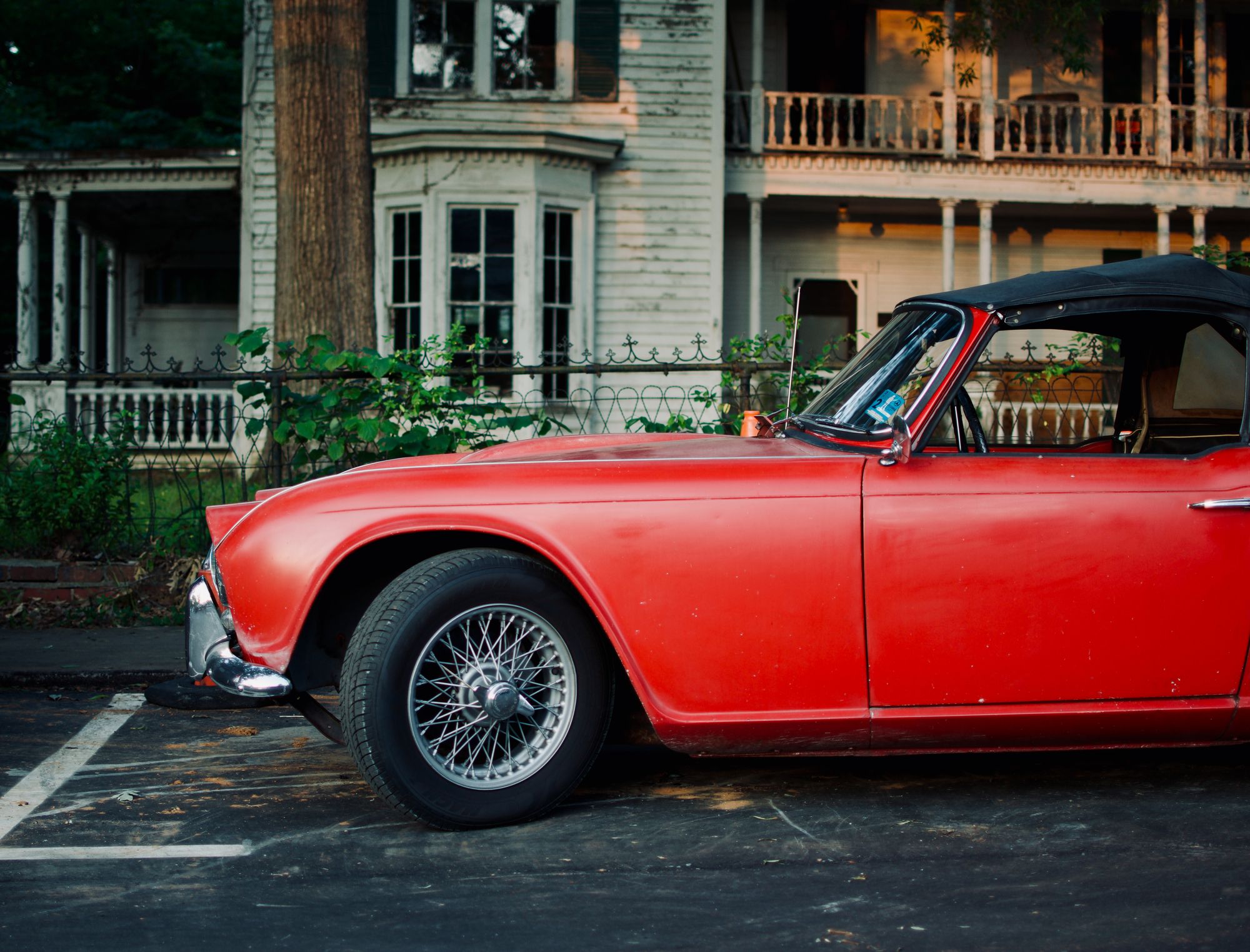 A vintage red roadster parked before an old Southern house, photographed by Mike Loerop