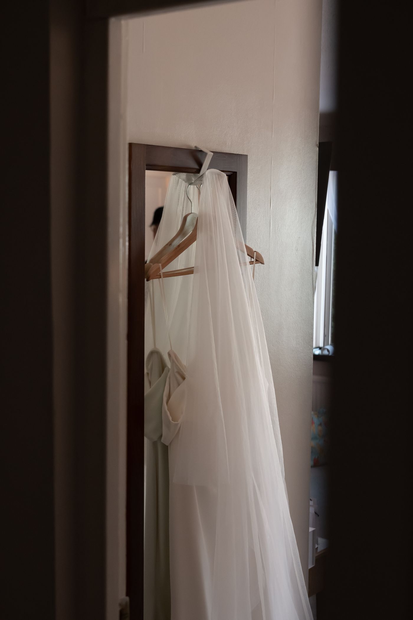 A wedding gown hanging in a softly lit doorway, photographed by Mike Loerop